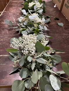 the long table is lined with eucalyptus leaves and white flowers