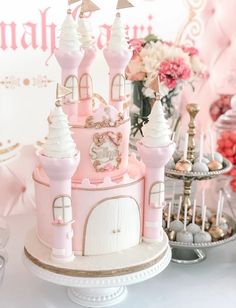 a pink princess castle cake sitting on top of a white table next to other desserts