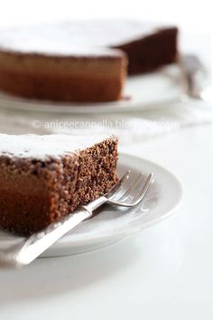 a slice of chocolate cake on a white plate with a silver fork next to it