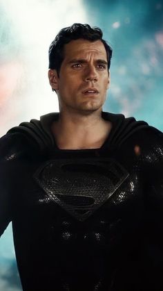 a man in a black superman suit with his hands on his hips