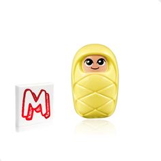 a yellow toy with a red m on it's face next to a white box