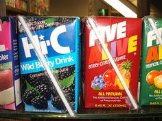 four juices are lined up on a shelf in a grocery store, one is blue and the other has blackberries