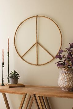 a wooden table topped with a potted plant and a peace sign hanging on the wall