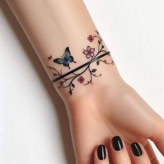 a woman's hand with a butterfly tattoo on her left wrist and black nail polish