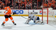 an ice hockey game in progress with the goalie getting ready to block the puck