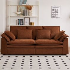 a brown couch sitting on top of a white floor next to a book shelf filled with books