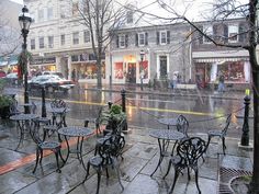 tables and chairs sitting on the sidewalk in the rain