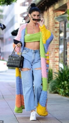 a woman walking down the street while talking on her cell phone and wearing ripped jeans