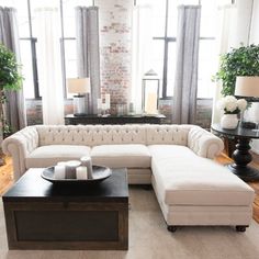 a living room with white couches and tables in front of two large windows that look out onto the street