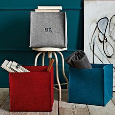 three different colored boxes sitting next to each other on the floor in front of a blue wall