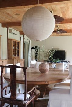 a round wooden table surrounded by white chairs