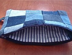 a blue and white patchwork pouch sitting on top of a wooden table next to a cell phone