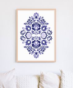 a blue and white art print hangs on the wall above a couch with pillows in front of it