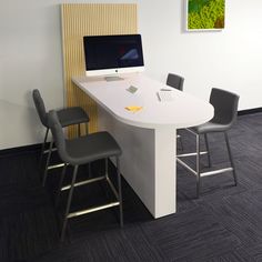 an office desk with two computers on it and four chairs around it, in front of a wall mounted monitor