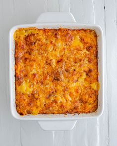 a casserole dish with cheese and meat in it on a white table top