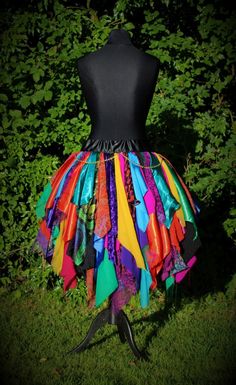 a mannequin wearing a colorful skirt in front of some green grass and bushes