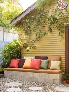 an image of a yellow house with red and green pillows on the front porch area