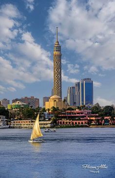 a sailboat on the water in front of a tall building