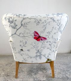 a white chair with a red butterfly on it's back and armrests