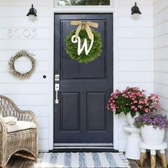 the front door is decorated with wreaths and two wicker chairs for sitting on