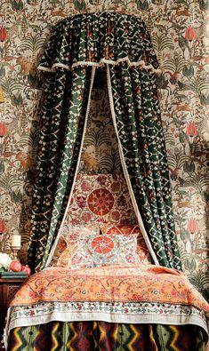 a bed with a canopy over it in front of a floral wallpapered wall