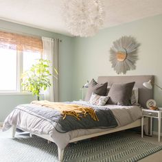 a bed sitting in a bedroom next to a window with a plant on top of it