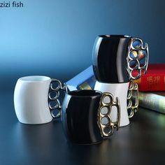 three black and white coffee mugs sitting next to books