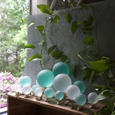 some green plants and blue glass balls on a shelf in front of a window sill