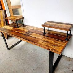 a table made out of wood and metal with two benches on each side, in front of a white wall