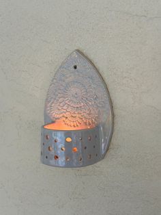 a light that is on the side of a wall with an orange candle in it