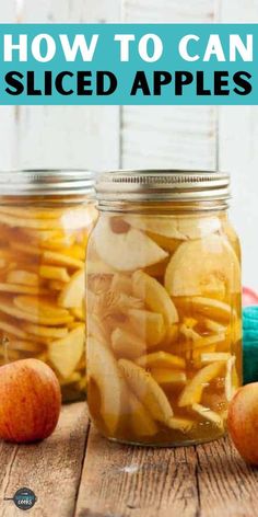 two jars filled with sliced apples on top of a wooden table next to an apple