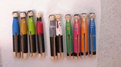 several wooden pegs are lined up in the shape of people with different colored tops