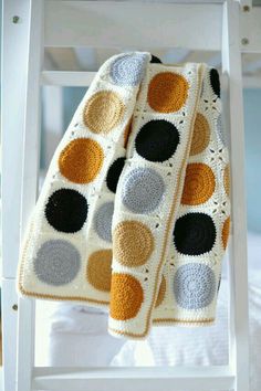 a crocheted blanket sitting on top of a white chair