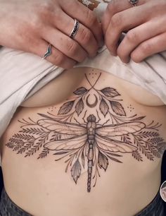 a woman's stomach with a dragonfly tattoo on it