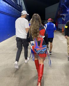 a woman in red boots walking down the street with other people behind her and one man wearing white