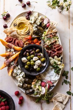 a platter filled with olives, cheese, meat and vegetables next to crackers