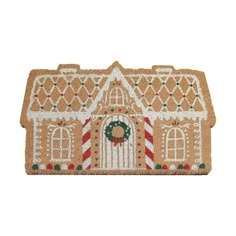 a gingerbread house door mat with a wreath on the front and an evergreen wreath at the top