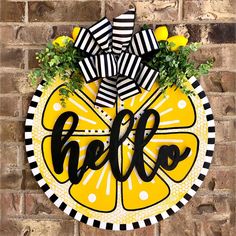 a yellow and black wreath with the word hello painted on it in front of a brick wall