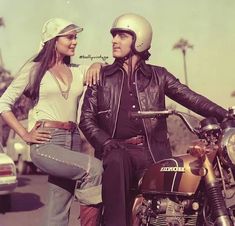 a man and woman standing next to each other on a motorbike in the street