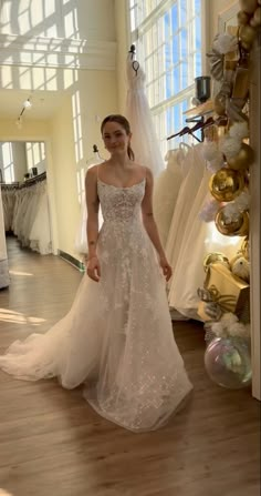 a woman standing in front of a wedding dress