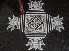 a person standing in the middle of a floor drawing with white chalk on black ground