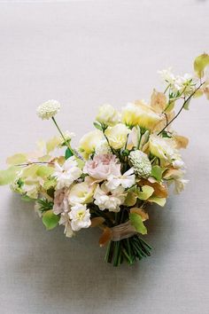 a bouquet of flowers sitting on top of a white cloth covered table next to a wall