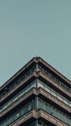 an airplane is flying in the sky above a tall building with windows and balconies