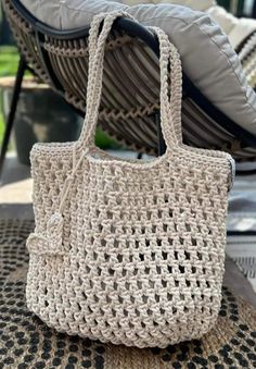 a crocheted bag sitting on top of a table next to a pillow and chair