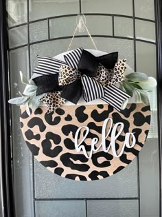 a leopard print door hanger with the word hello on it and a black bow