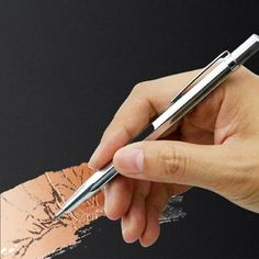 a person is holding a pen and writing on the side of a piece of paper