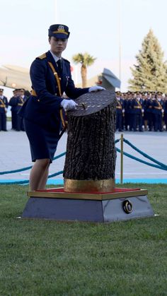 a woman in uniform standing next to a tree stump with other uniformed people behind her