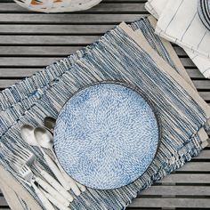 a blue and white plate sitting on top of a table next to utensils