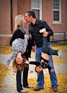 a man and woman kissing while standing next to each other in front of a brick building