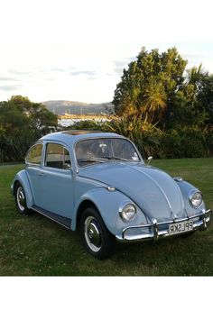 an old blue car is parked in the grass